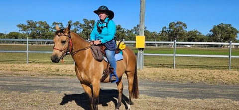 Kylie riding her horse with the Adventurer on her saddle