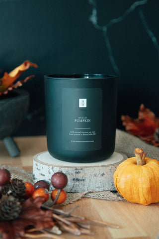 Best fall candle, Hello Pumpkin hand-poured soy candle on birch log next to a fall arrangement of pumpkin, autumn leaves and berries.