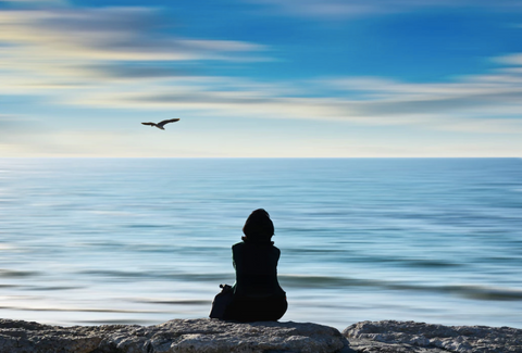 person at the beach meditating