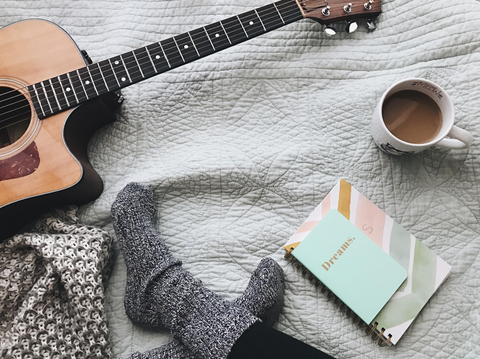 Sitting on couch with a guitar, journal and cup of tea