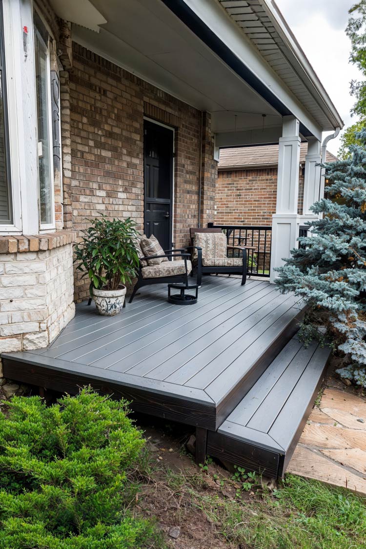 traditional patio deck with step and chairs against brick home