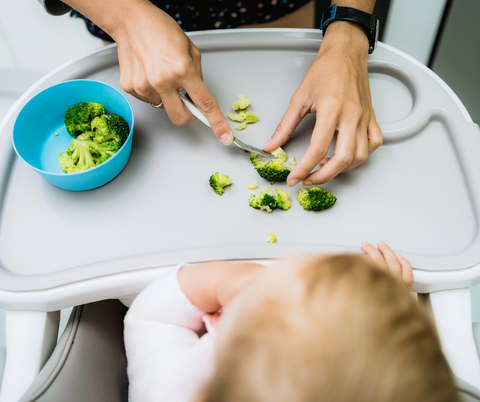 cutting broccoli on a highchair table