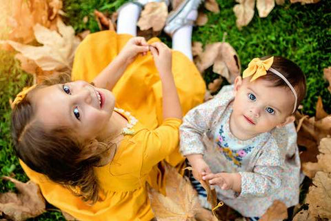 two girls in fancy dresses looking up at camera