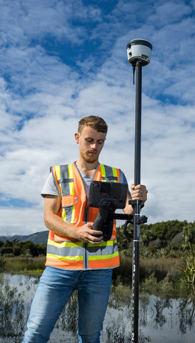 Young man holding Trimble R580 and TSC7 in swampy area