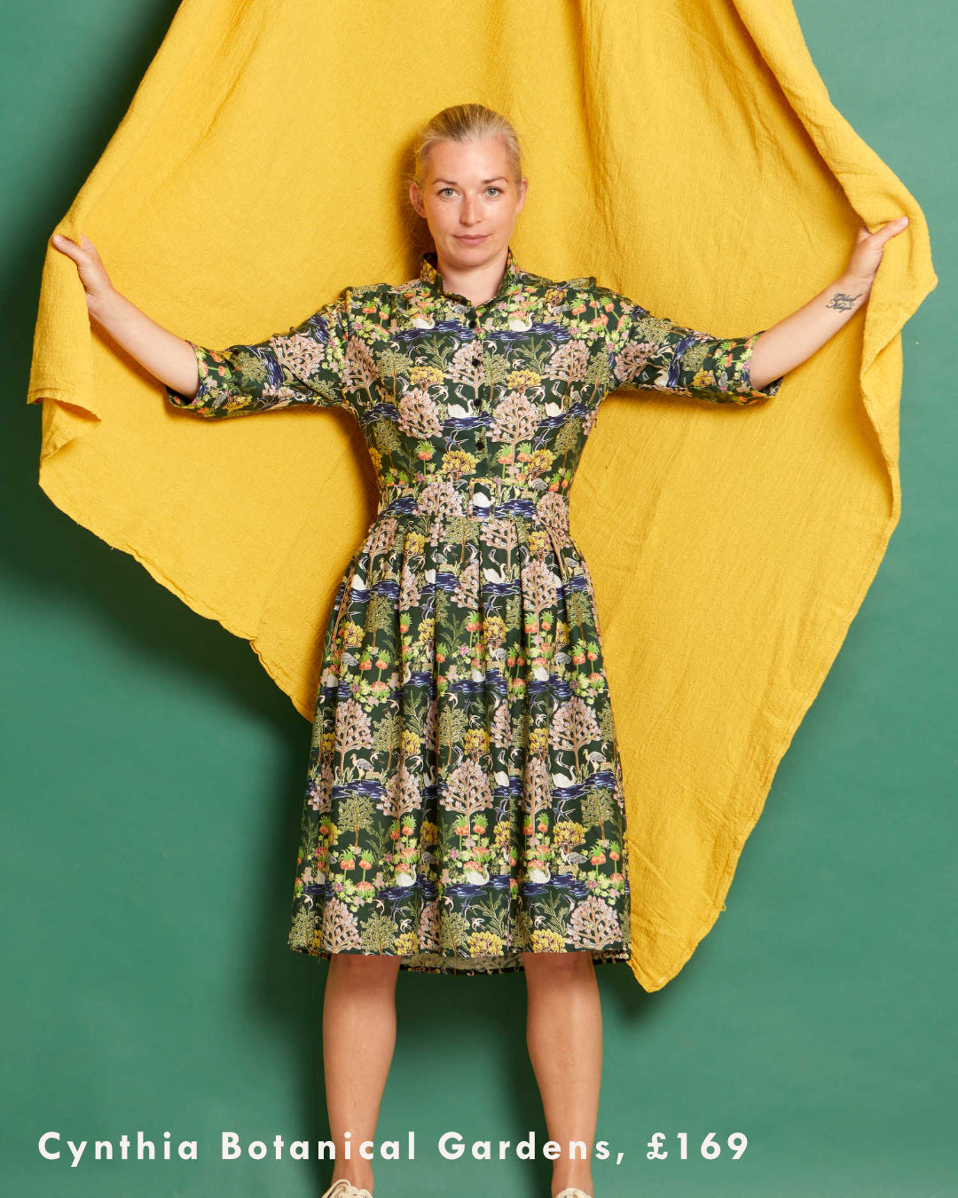 Woman wearing a printed shirt dress in front of a yellow and green background