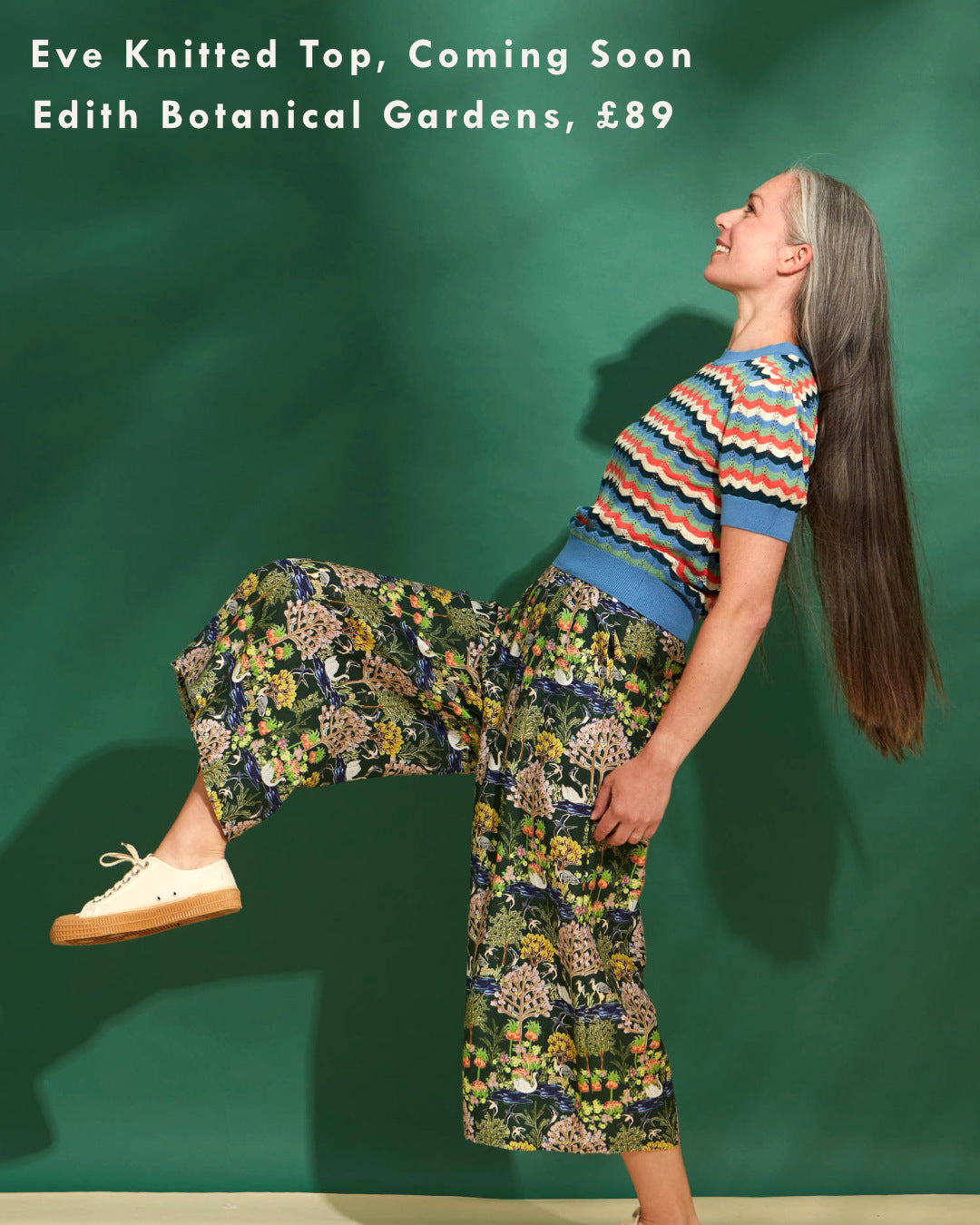 A woman wears printed wide-leg culottes with a striped mineral blue and orange knitted top.