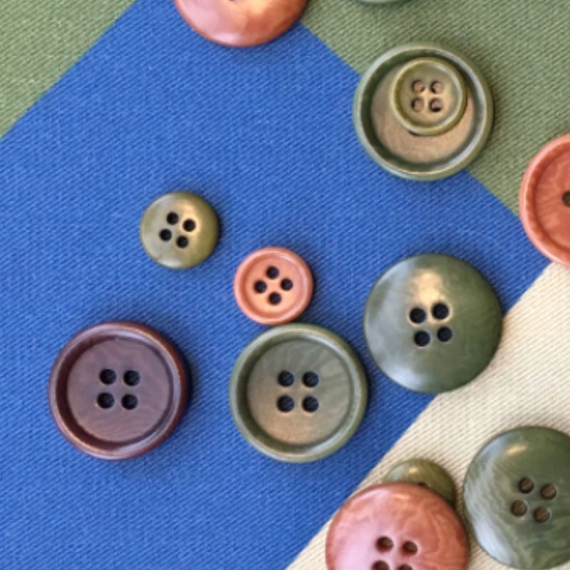 A photo of corozo nut buttons laid out on blue green and beige fabric