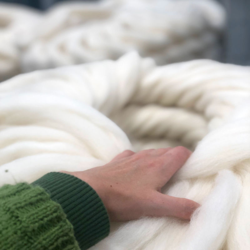 a picture of a large roll of wool being touched by a hand. 