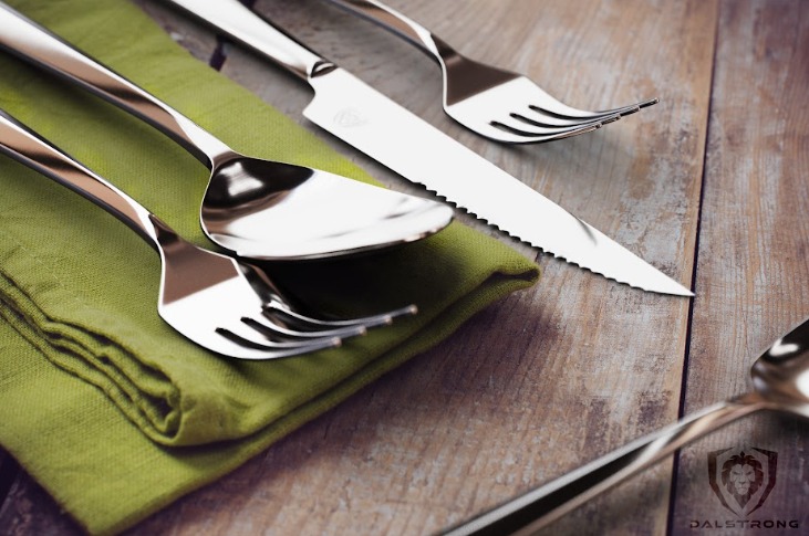 A close-up photo of the 20-Piece Flatware Cutlery Set Service for 4 Stainless Steel Dalstrong on top of a wooden table.