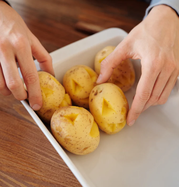 A photo of a hand and five potatoes in a container.