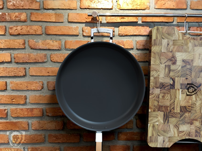 A photo of the 12" Sauté Frying Pan Silver | Oberon Series | Dalstrong with the dalstrong cutting board in the side.