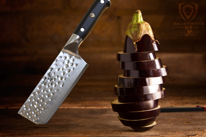 A photo of the Nakiri Vegetable Knife 6" Shogun Series ELITE | Dalstrong with a stack of sliced egg plant