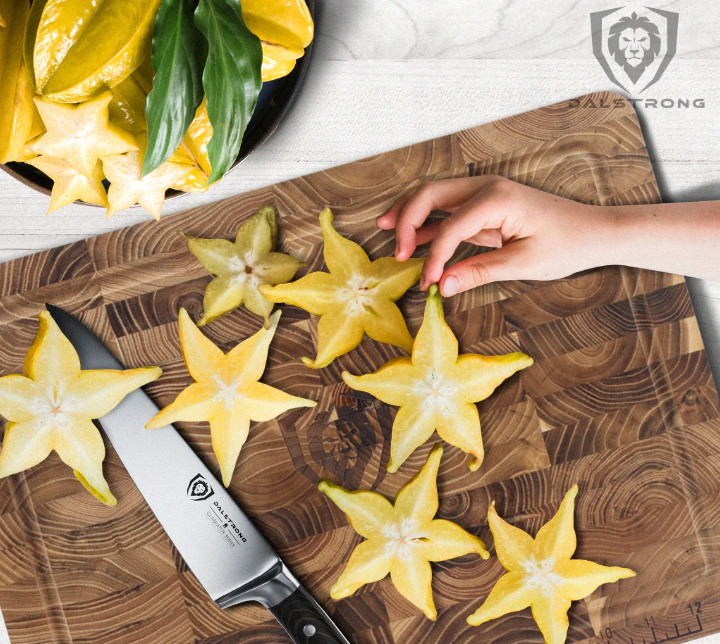 A photo of the Chef's Knife 7" Gladiator Series | NSF Certified | Dalstrong with seven slices of star fruit on top of a Dalstrong wooden board.