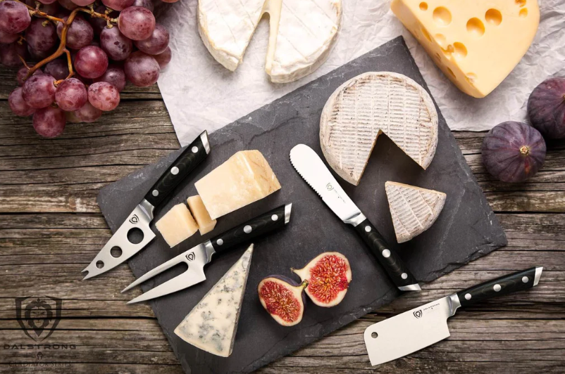 Different cheese slices laid on a cutting board with Dalstrong Gladiator Cheese Knife Set