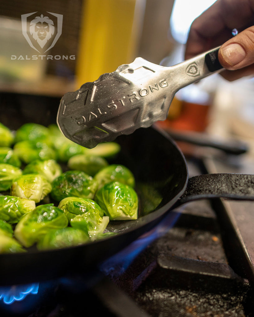 Dalstrong Food Tongs 9" Stainless Steel Arms & Scalloped Tips in a pan of brussels sprouts