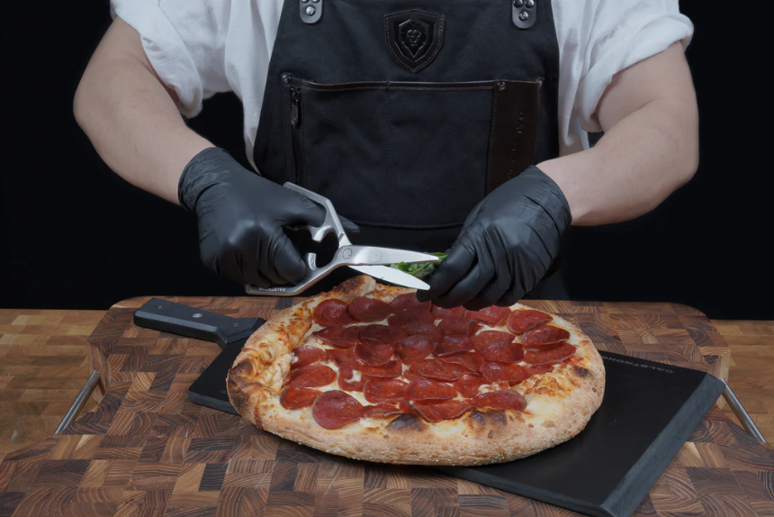 A man holding the Professional Kitchen Scissors | 420J2 Japanese Stainless Steel | Dalstrong with pizza on a cutting board.
