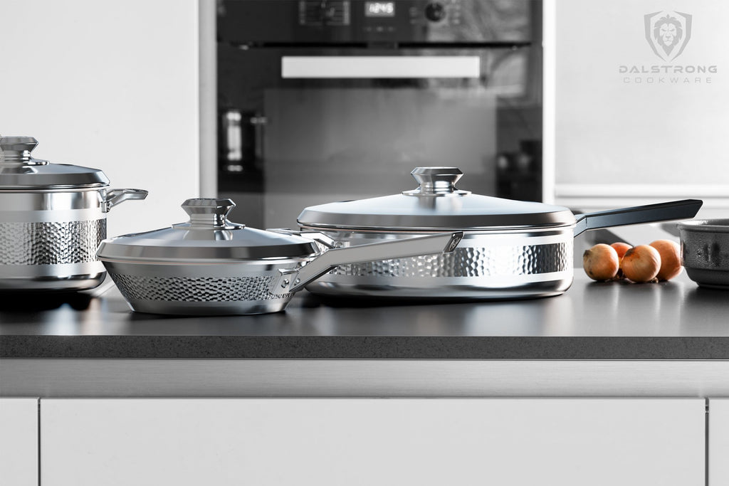 Stainless steel cookware on a dark kitchen counter with an oven in the background