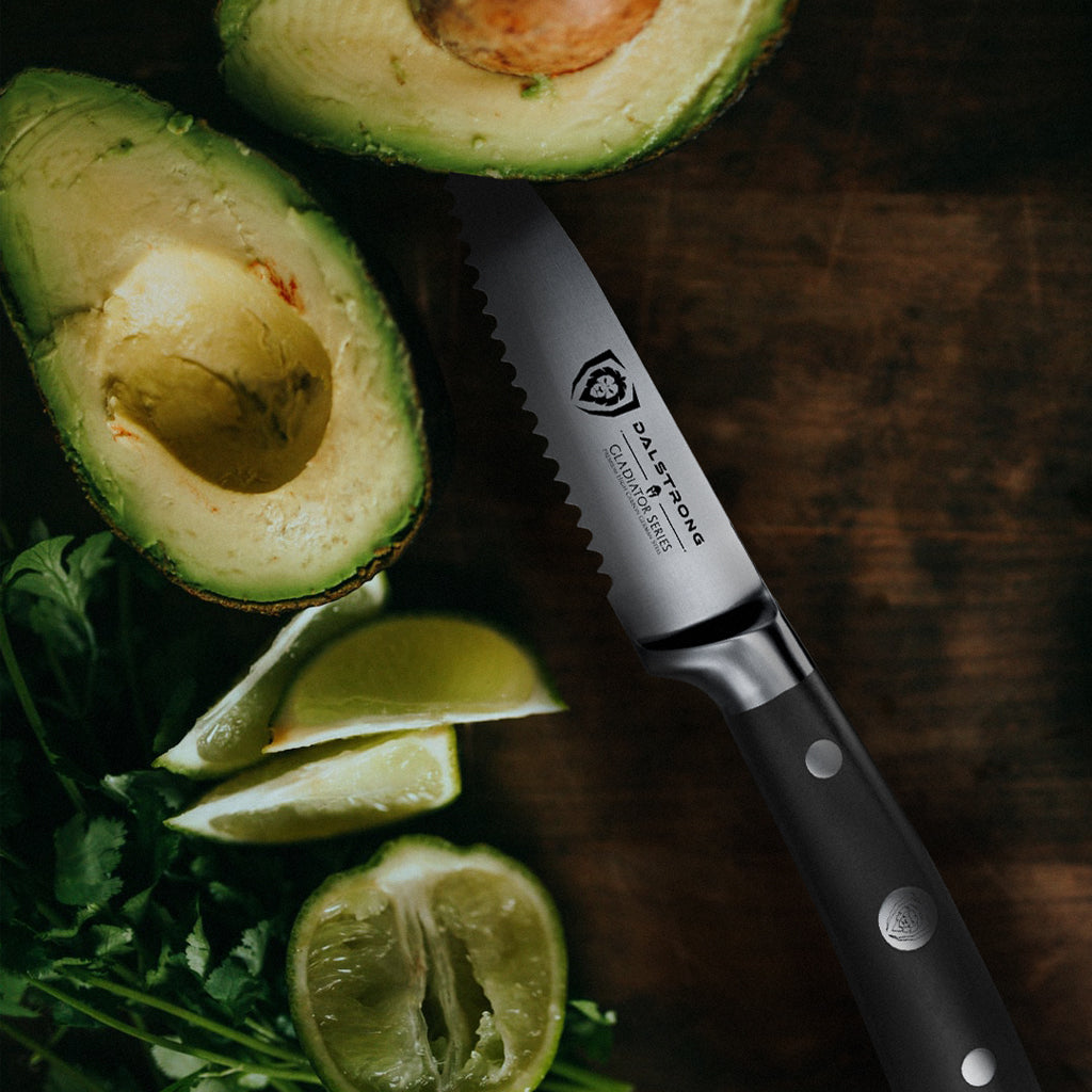 Avocados cut in half on a teak cutting board with a utility knife