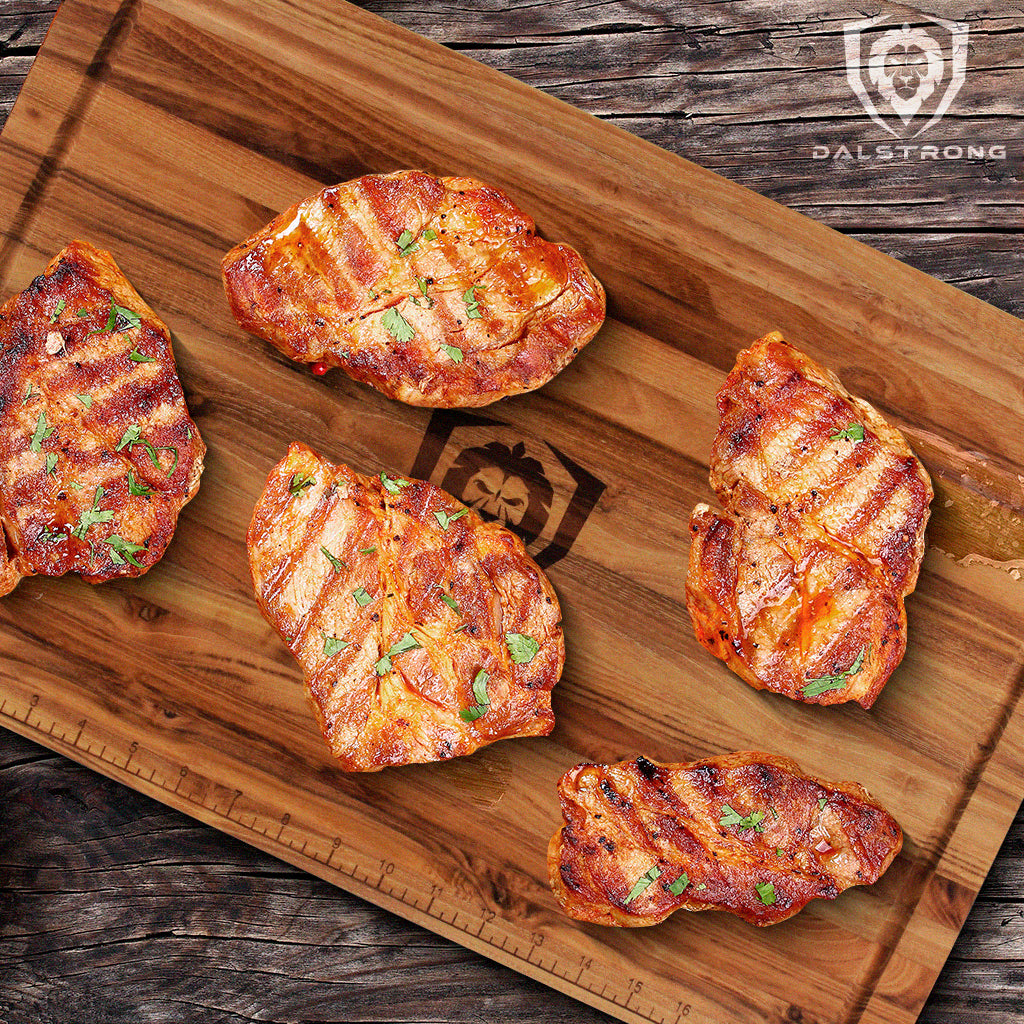 Delicious boneless porkchops on top of a Dalstrong wooden teak board.