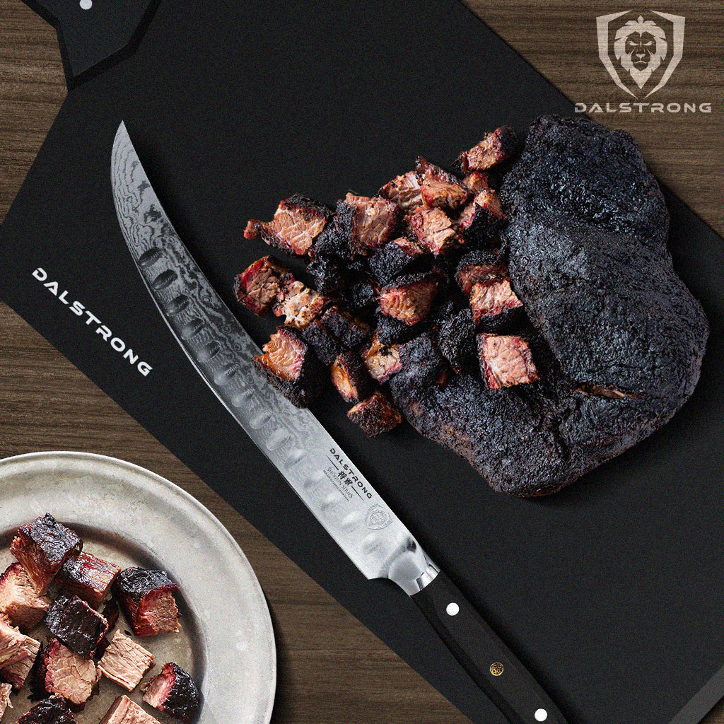 Large butcher knife on a black cutting board next to brisket burnt ends