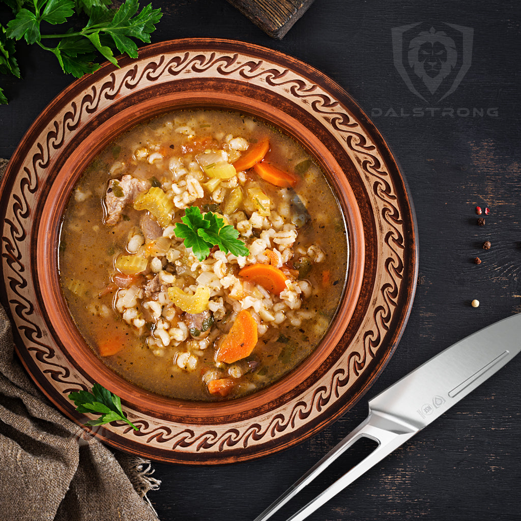 Bowl of beef and barley soup laying beside paring knife