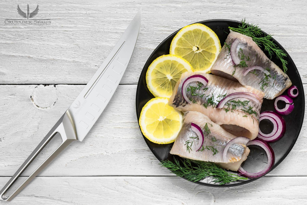 Stainless Steel fillet knife with hollow handle next to a plate of uncooked fish and sliced lemon