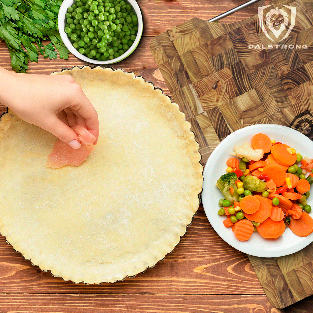 Pie shell with chicken pot pie ingredients on Dalstrong teak cutting board