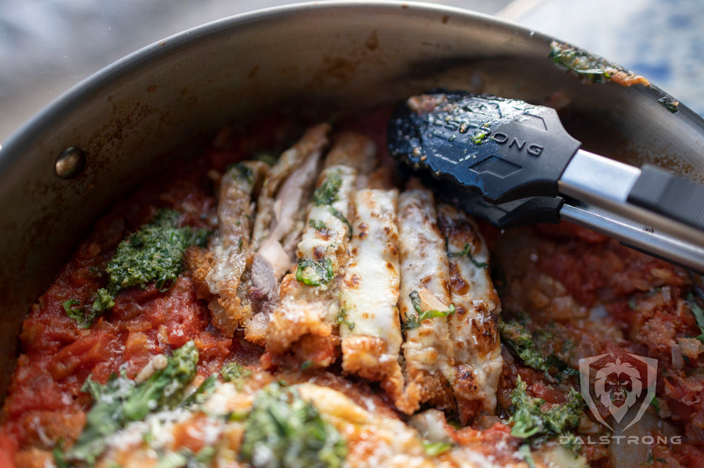 Dalstrong Food Tongs 12" with Scalloped Silicone Tips in a pan of cooked chicken