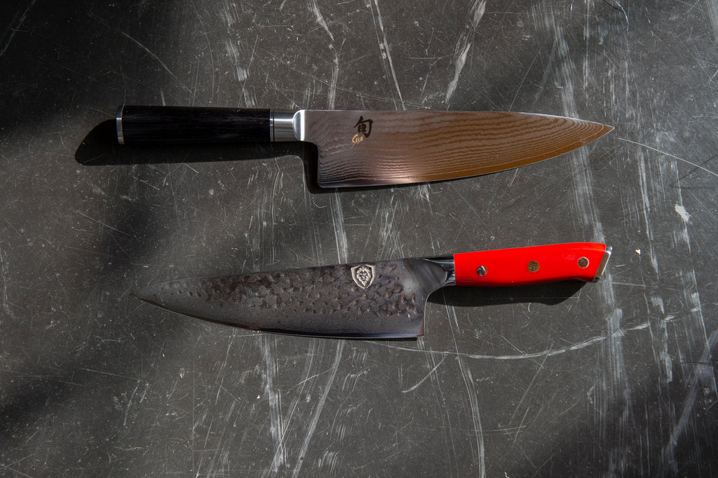 Dalstrong knife next to a shun knife on a dark grey surface