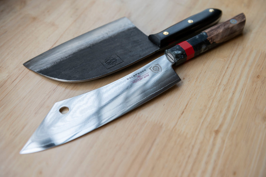 An angled shot of a Dalstrong and Coolina knife on a wooden surface.