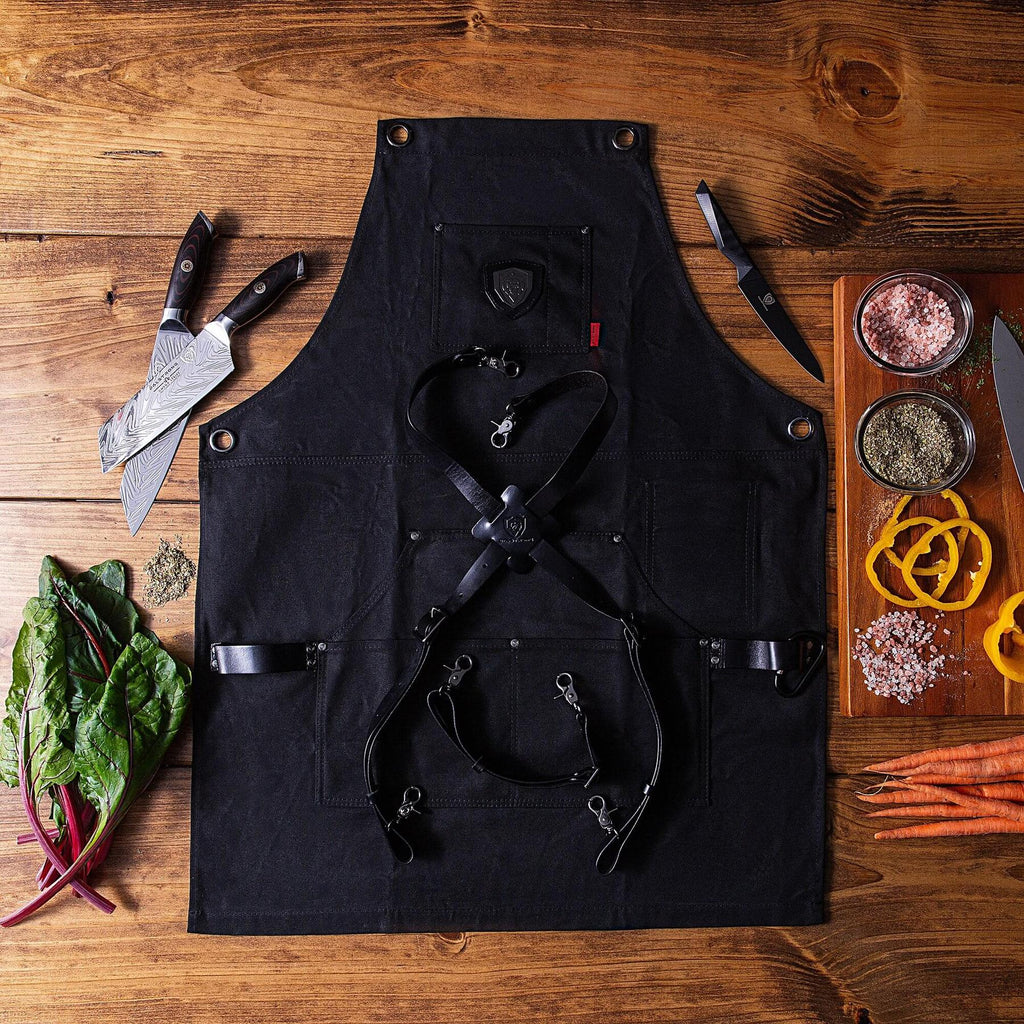 Black kitchen apron on a wooden floor next to chopped food and a kitchen knife