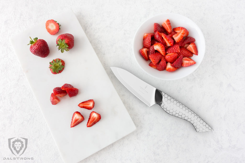 Dalstrong Frost Fire Series Paring Knife on a white counter with slices of fresh strawberries.