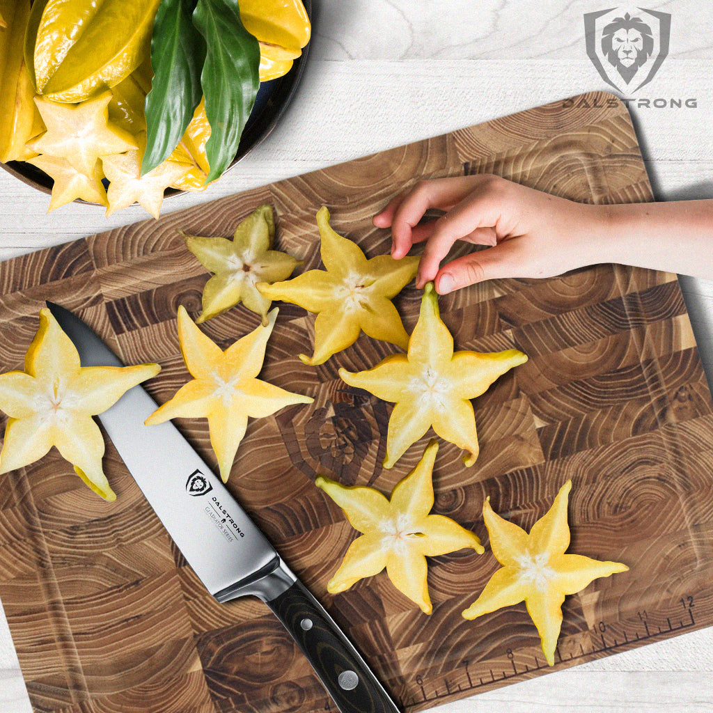 A hand picking up star fruit from a cutting board