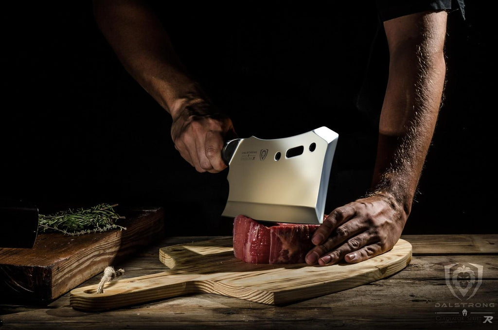 Man uses large cleaver to chop raw piece of red meat