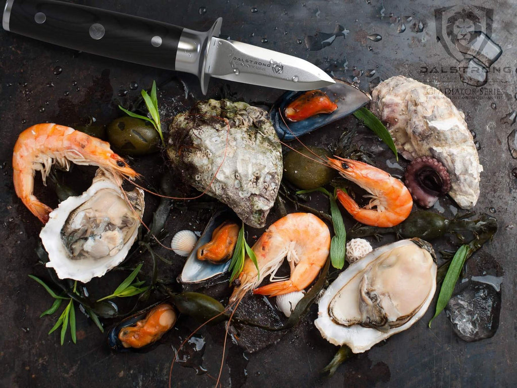 Prawns and oysters and clams next to a oyster shucking knife on a black surface