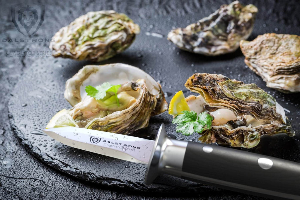 An oyster shucking knife next to a dark plate of oysters