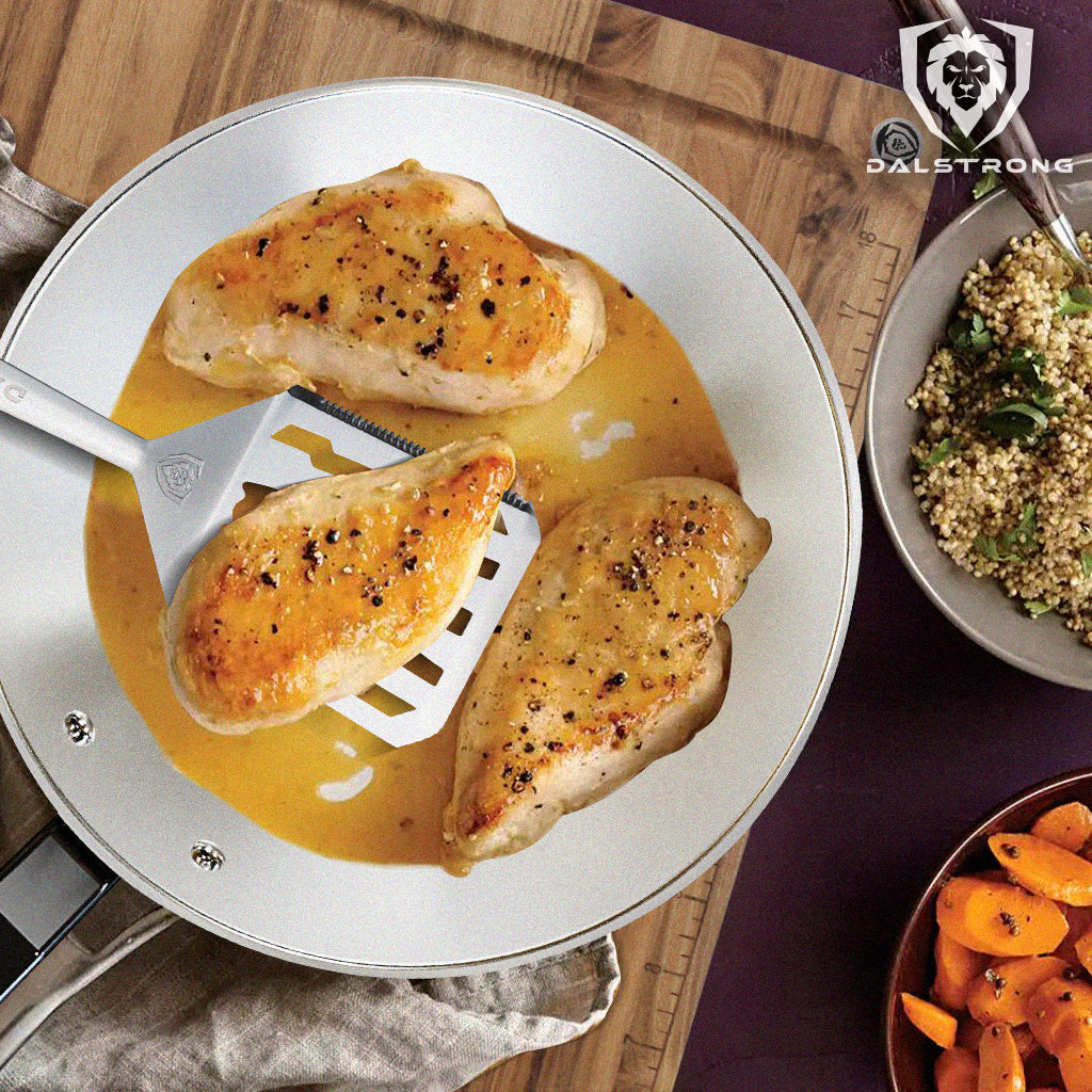 Greek chicken on Dalstrong spatula above full pan of chicken