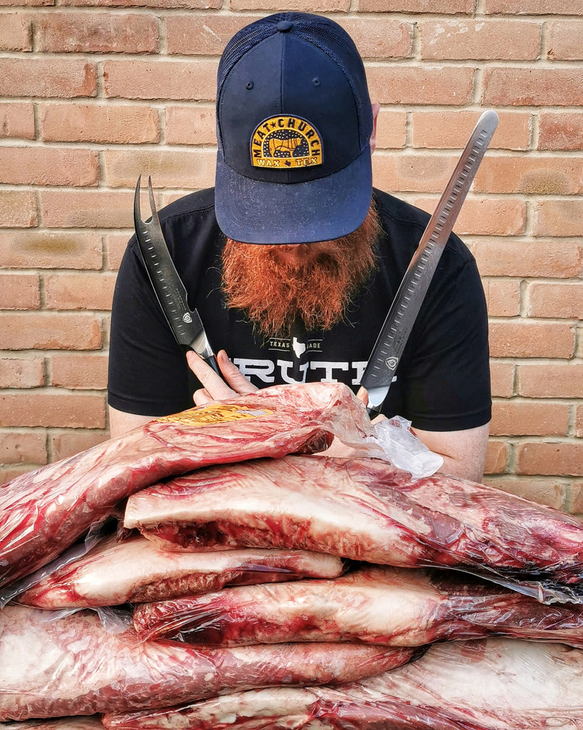 Artust BBQ (@ArtustBBQ) posing in front of meat holding two Dalstrong knives