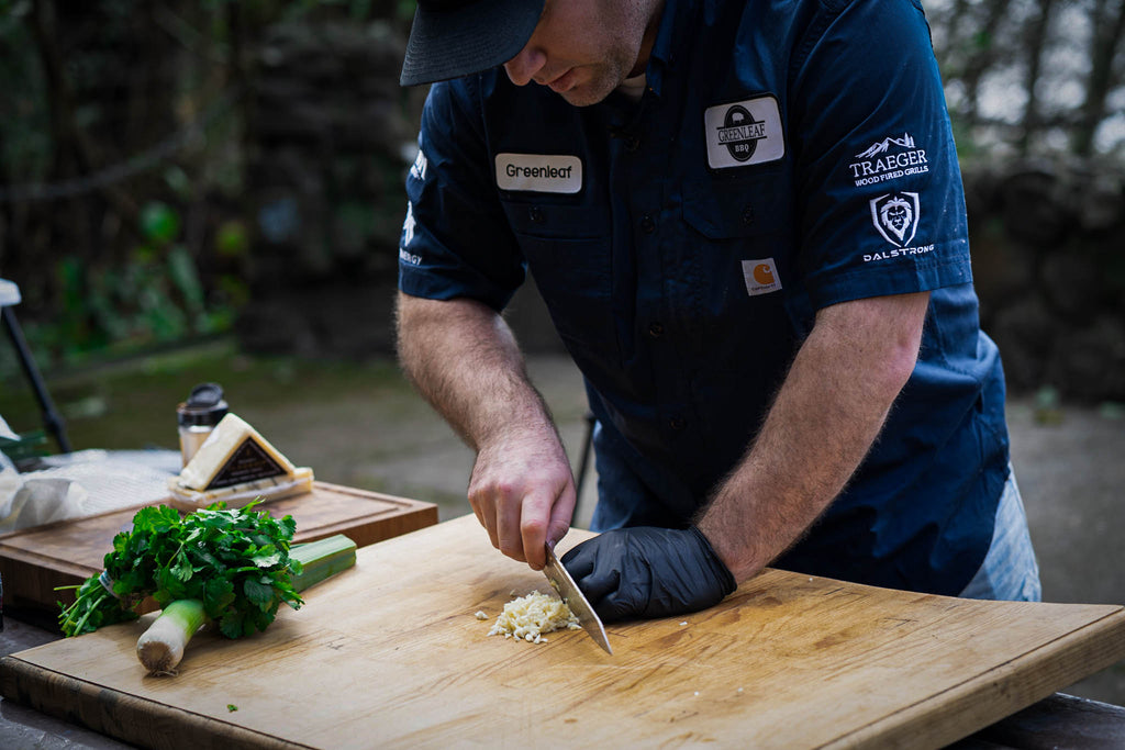 ChJames Greenleaf (@greenleaf.bbq) chopping garlic outdoors with a Dalstrong knife