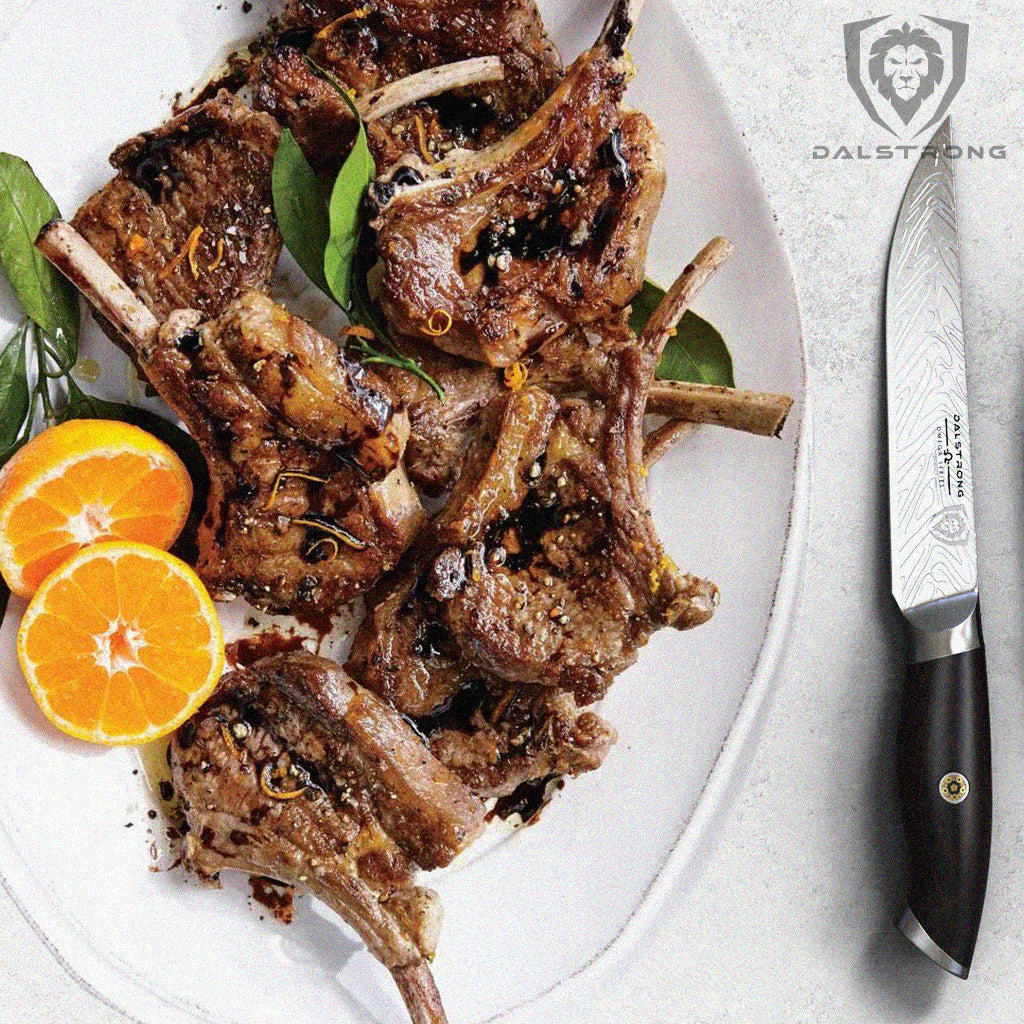 A plate of lamb chops next to a sharp kitchen knife