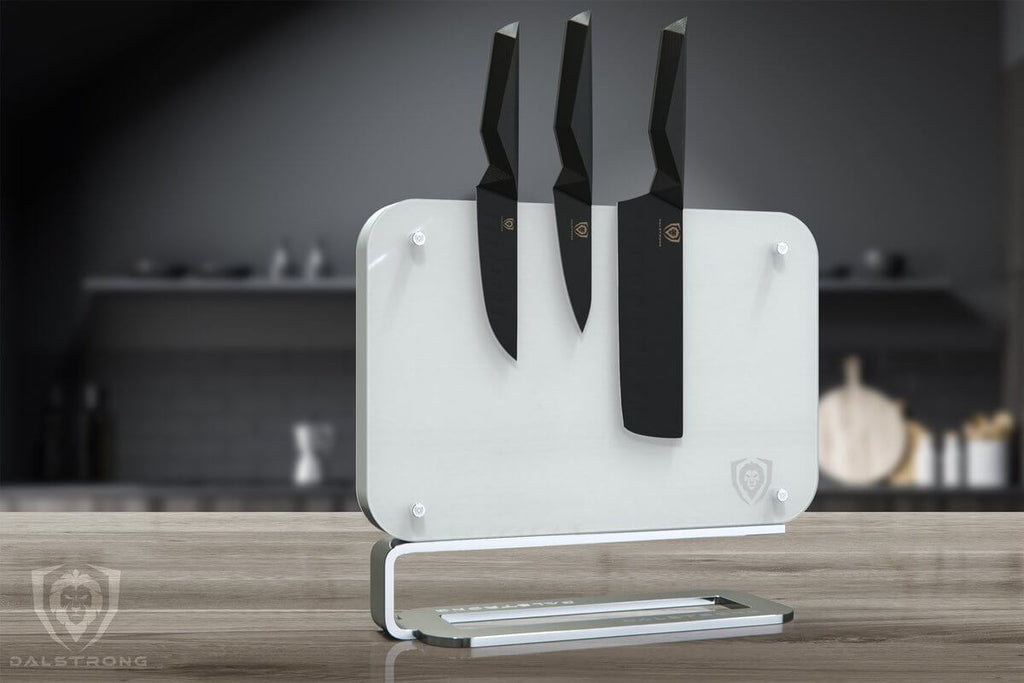 Dalstrong white magnetic knife block on a wooden surface with Shadow Black Knife Series attached to it.