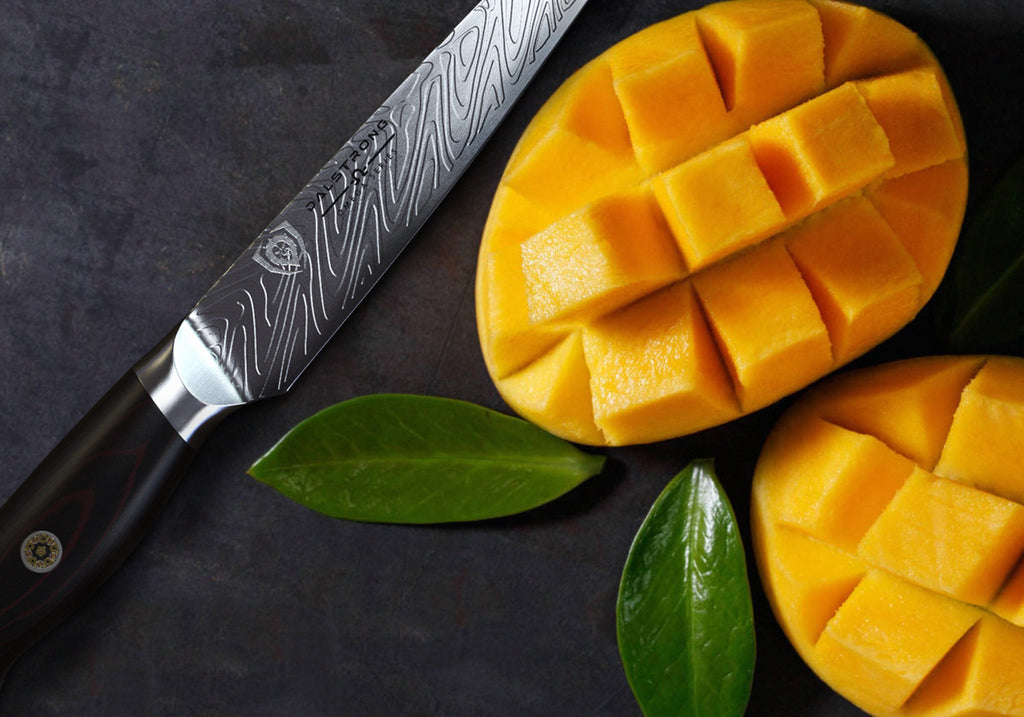 Sharp paring knife next to cubed pieces of mango