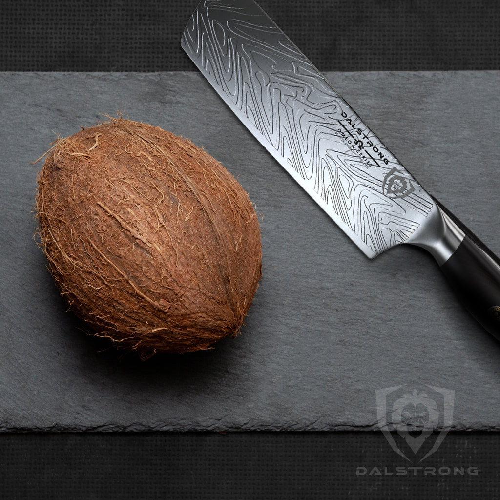 nakiri knife laying beside a unopened coconut