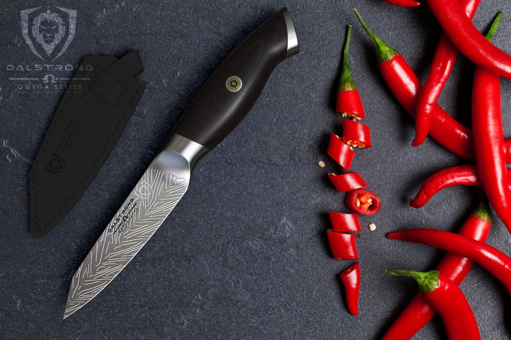 Paring knife on a dark surface next to chopped red chilli pepper 