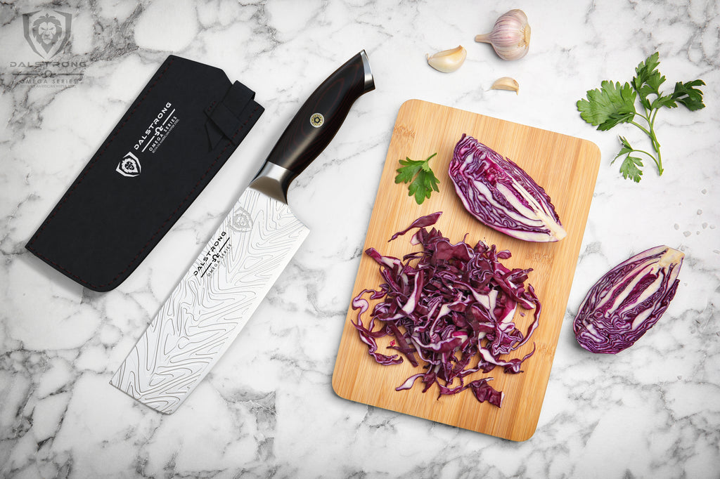 Nakiri knife on marble counter next to a wooden cutting board with diced red onion