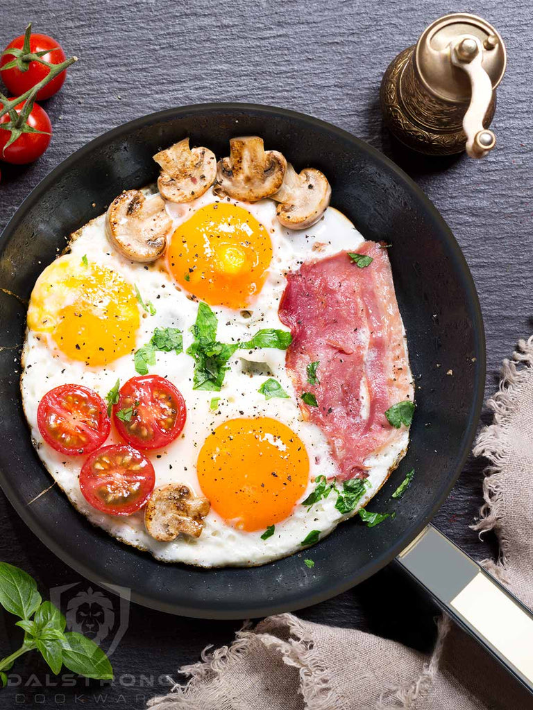 A skillet with fried eggs mixed with bacon tomatoes and mushrooms