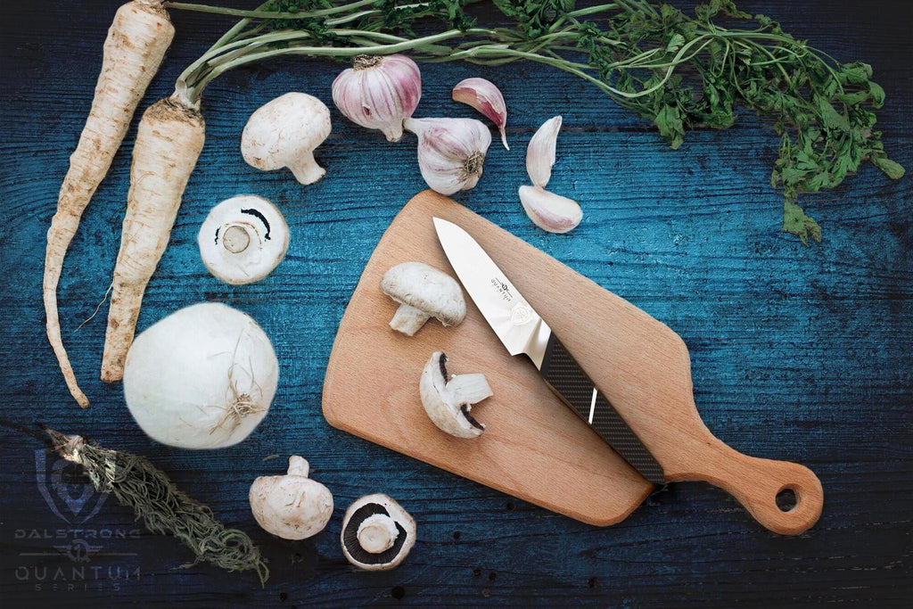 A blue wooden surface with mushrooms and parsnips next to a cutting board with a paring knife on it