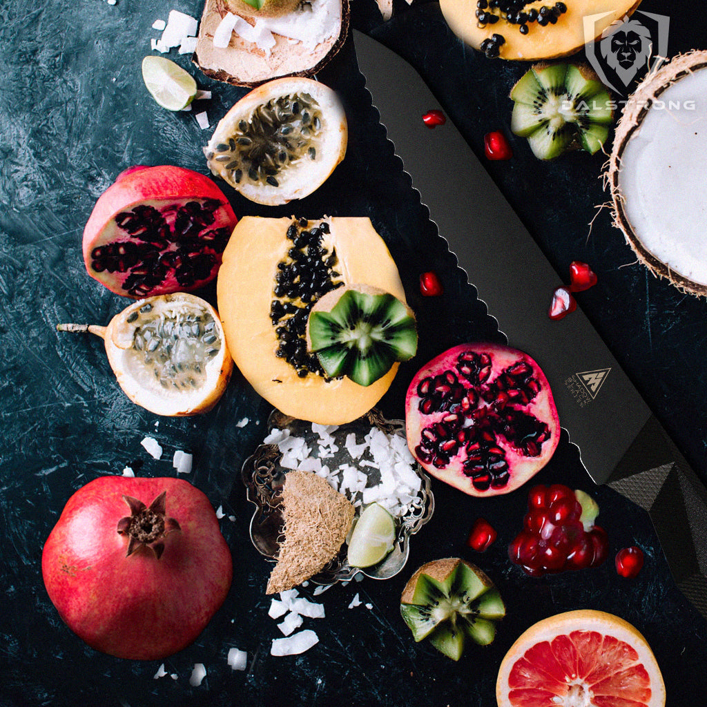 A selection of fruits including pomegranate next to a serrated black kitchen knife