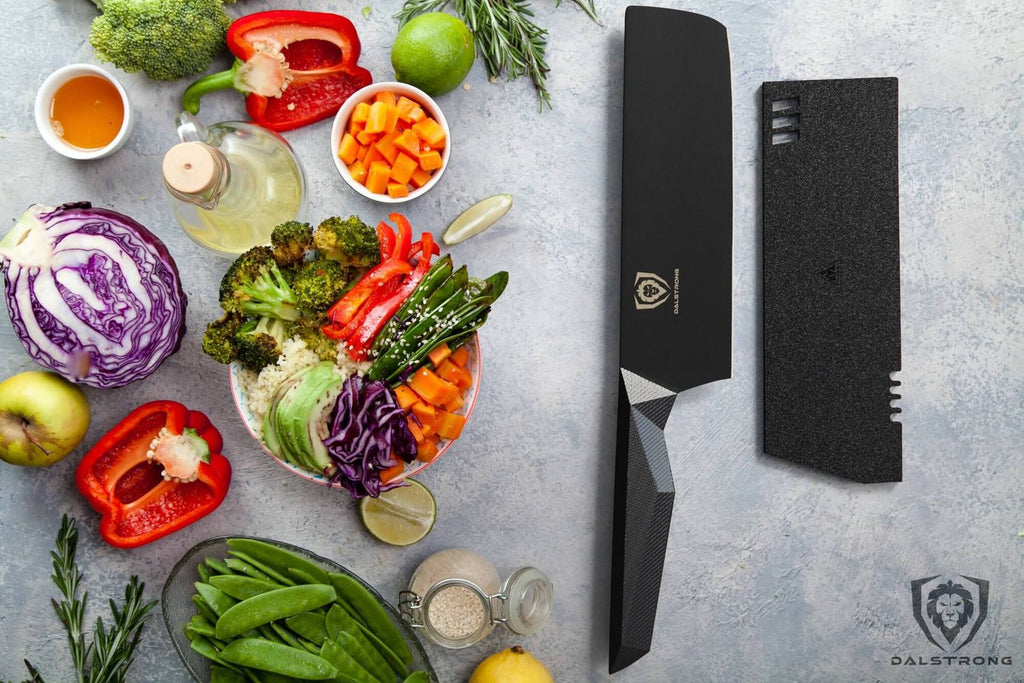 A wide variety of chopped vegetables on a grey surface next to a black nakiri knife