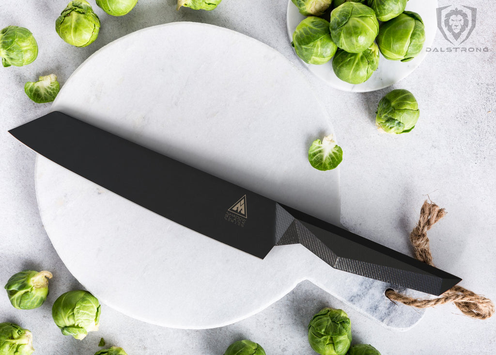 Black Kiritsuke knife on a marble cutting board surrounded by Brussels sprouts